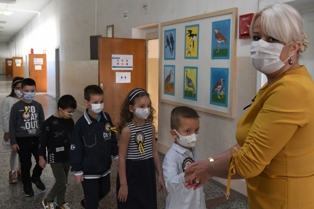 Montenegrin schoolchildren wearing protective masks to prevent the spread of the novel coronavirus (Covid-19) wait in line with their teacher on the first day of the new school year in Podgorica, on September 30, 2020. / AFP / Savo Prelevic 