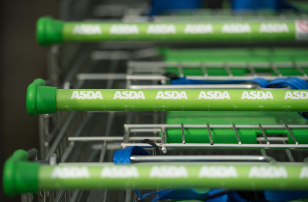 In this file photo taken on April 30, 2018 logos of supermarket chain Asda are pictured on the handles of shopping trolleys outside a store in Stockport, northern England US retail giant Walmart has agreed to sell its British supermarket chain Asda to two