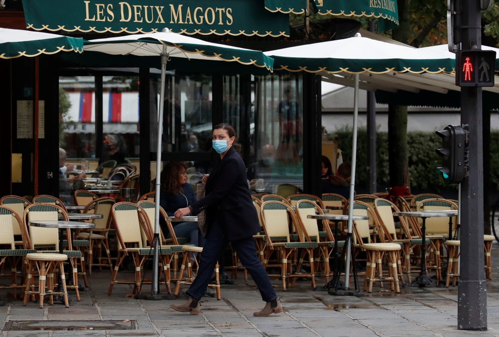 A woman wearing a protective face mask walks past the cafe and restaurant Les Deux Magots in Paris, during the announcement of new Covid restrictions by Paris authorities as the coronavirus disease (COVID-19) outbreak continues in France, October 5, 2020.