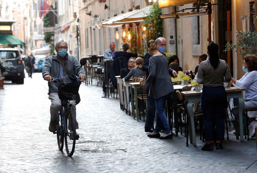 A man rides a bike, as local authorities in the Italian capital Rome order face coverings to be worn at all times out of doors in an effort to counter rising coronavirus disease (COVID-19) infections, in Rome, Italy October 6, 2020. REUTERS/Remo Casilli