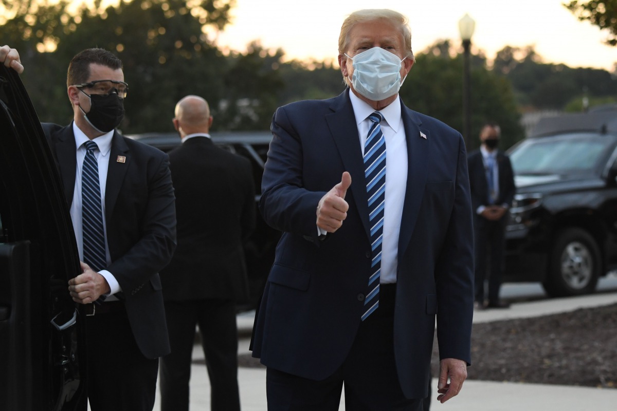 TOPSHOT - US President Donald Trump gestures after walking out of Walter Reed Medical Center in Bethesda, Maryland before heading to Marine One on October 5, 2020, to return to the White House after being discharged. Trump announced he would be 
