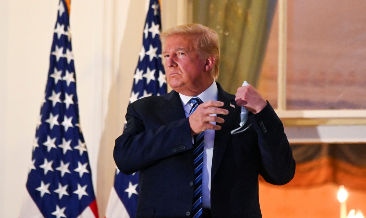 U.S. President Donald Trump pulls off his protective face mask as he poses atop the Truman Balcony of the White House after returning from being hospitalized at Walter Reed Medical Center for coronavirus disease (COVID-19) treatment, in Washington, U.S. O