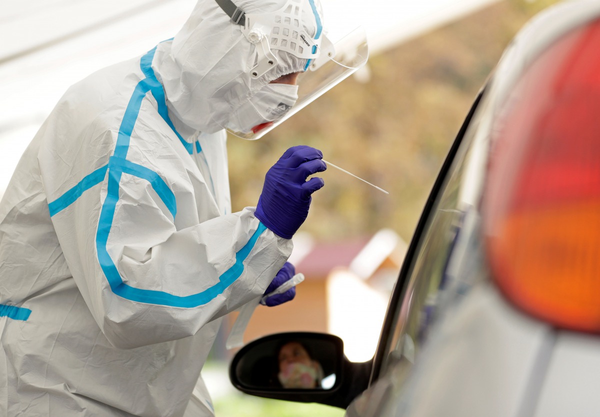 A medical staff member wearing a protective suit takes a swab as people are tested for the coronavirus disease (COVID-19) at a newly opened drive-in sampling station in Prague, Czech Republic, October 7, 2020. REUTERS/David W Cerny
