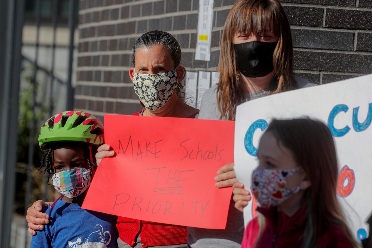 Parents and children hold signs during a protest against the closing of Public School 130 outside the school building for safety reasons, following the outbreak of the coronavirus disease (COVID-19) in the Brooklyn borough of New York City, U.S., October 