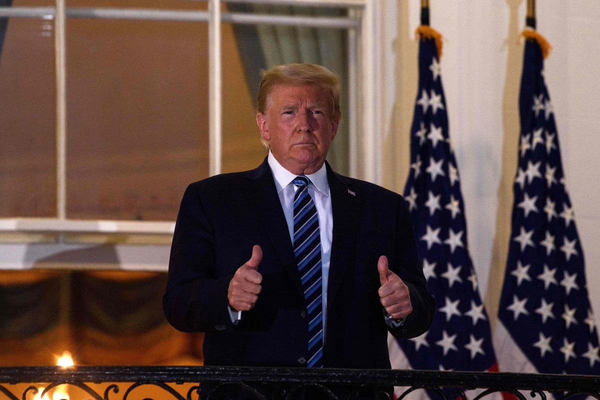 (FILES) In this file photo taken on October 05, 2020 US President Donald Trump gives two thumbs up from the Truman Balcony upon his return to the White House from Walter Reed Medical Center, where he underwent treatment for Covid-19, in Washington, DC./ A