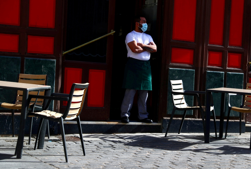 A waiter wearing a protective face mask waits for customers in his terrace amid the outbreak of the coronavirus disease (COVID-19), in Madrid, Spain October 1, 2020. REUTERS/Sergio Perez/File Photo/File Photo