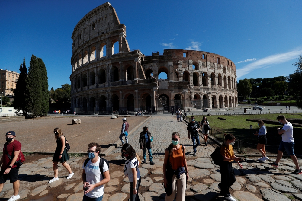 People wearing protective face masks walk past the Colosseum as local authorities in the Italian capital Rome ordered face coverings to be worn at all times outdoors, in an effort to counter the spread of the coronavirus disease (COVID-19), in Rome, Italy