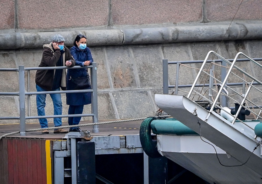 People wearing face masks to protect against the coronavirus disease stand on a pier as they wait for a pleasure boat in central Moscow on October 13, 2020. / AFP / Yuri KADOBNOV