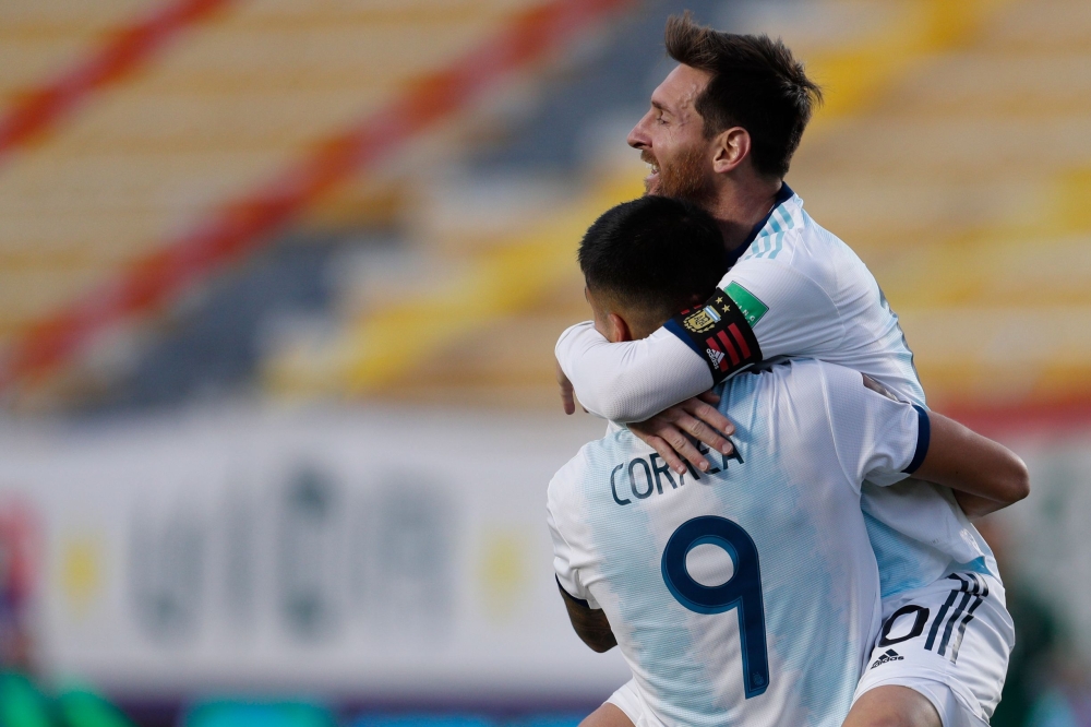 Argentina's Joaquin Correa celebrates with teammate Lionel Messi (top) after scoring against Bolivia during their 2022 FIFA World Cup South American qualifier football match at the Hernando Siles Stadium in La Paz on October 13, 2020, amid the COVID-19 no