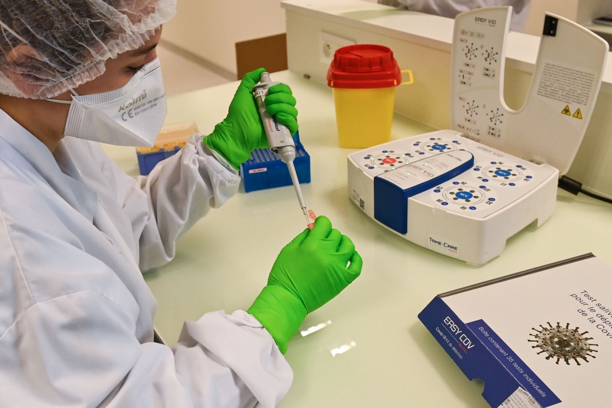 A researcher from the Sys2Diag laboratory, from the biotechnology company SkillCell, holds a saliva sample to perform a rapid screening for Covid-19, in Montpellier, southern France, on October 13, 2020. / AFP / Pascal GUYOT
