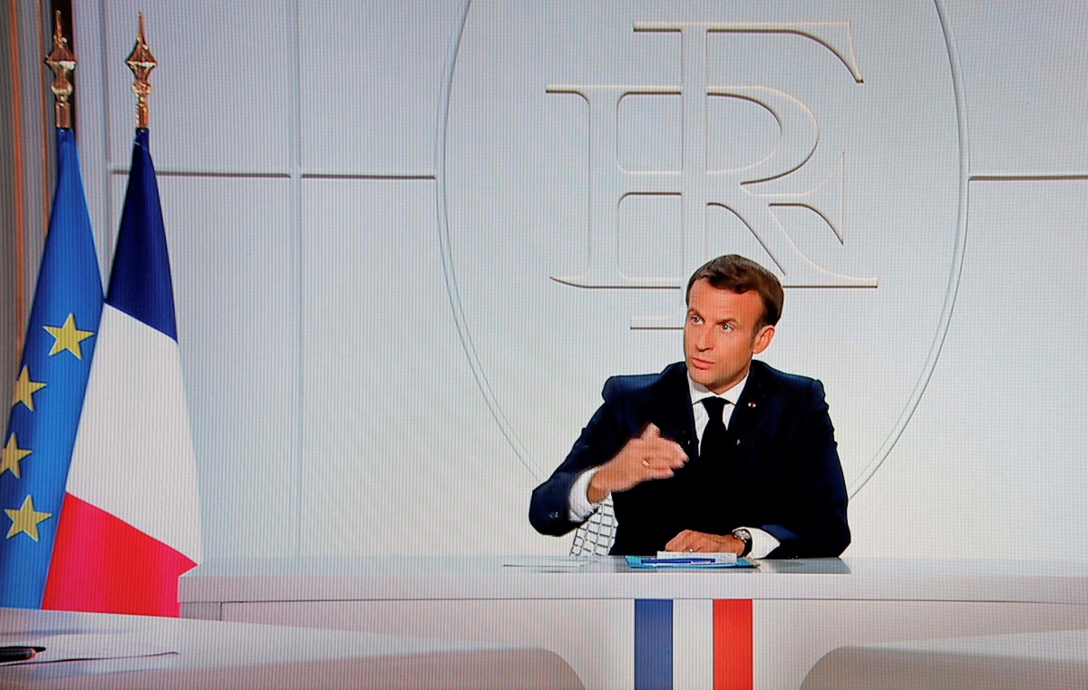 This picture shows a screen displaying French President Emmanuel Macron as he addresses the nation during a televised interview from the Elysee Palace concerning the situation of the novel coronavirus Covid-19 in France, in Paris on October 14, 2020.