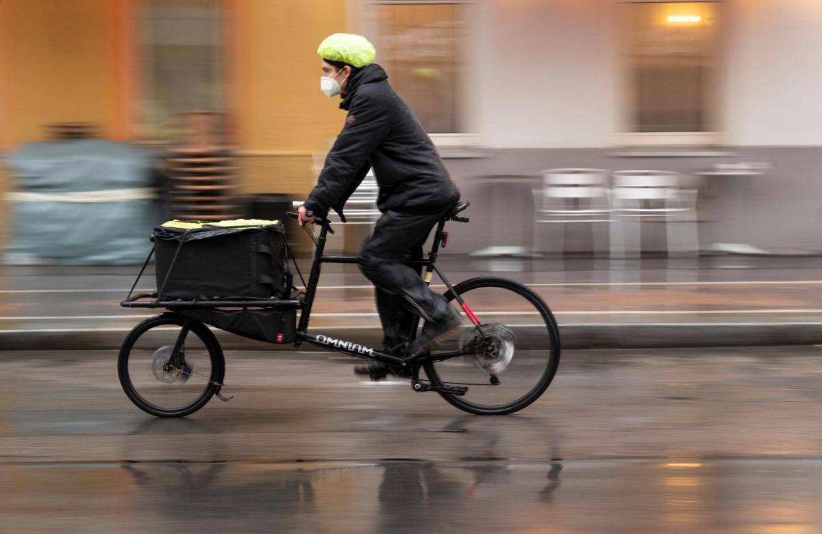 Marcus Hanould, 25 year's old bicycle courier of Veloce company, rides his bike to a residential building to deliver Covid-19 tests and bring them back to a lab in Vienna, Austria on October 13, 2020. / AFP / JOE KLAMAR

