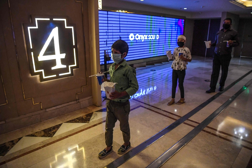 People invited as 'Covid-19 warriors' and their families to a special screening of Bollywood movie 'Tanhaji' queue to enter a cinema auditorium in New Delhi on October 15, 2020, with some states still keeping theatres closed amid the Covid-19 coronavirus 
