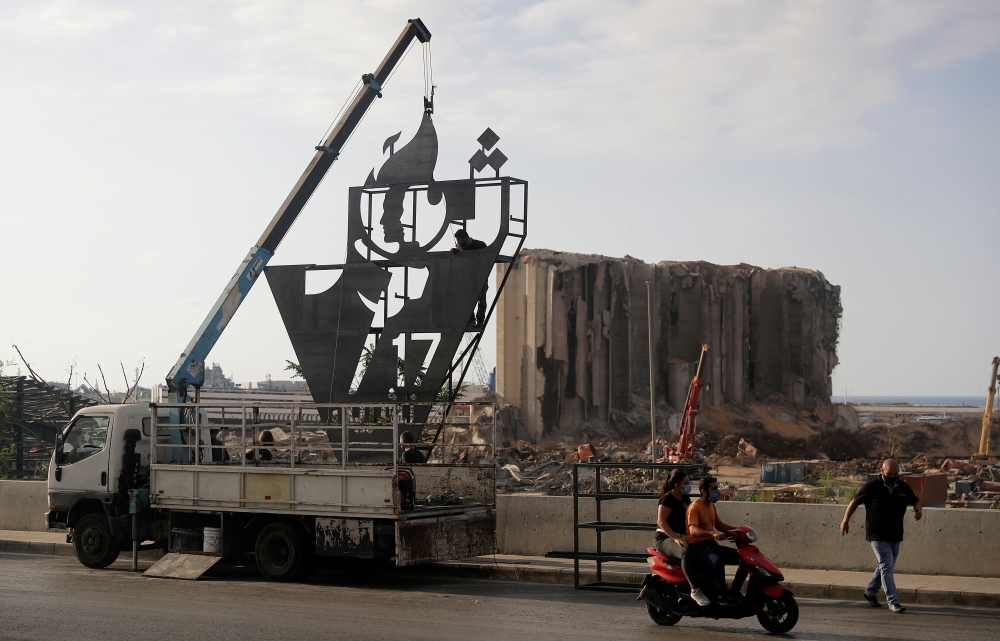 Lebanese activists erect a metalic monument on October 16, 2020, with 'October 17' written on it in Arabic, a day ahead of the one year anniversary of the beginning of a nationwide anti-government protest movement, in front of the devastated port of the c