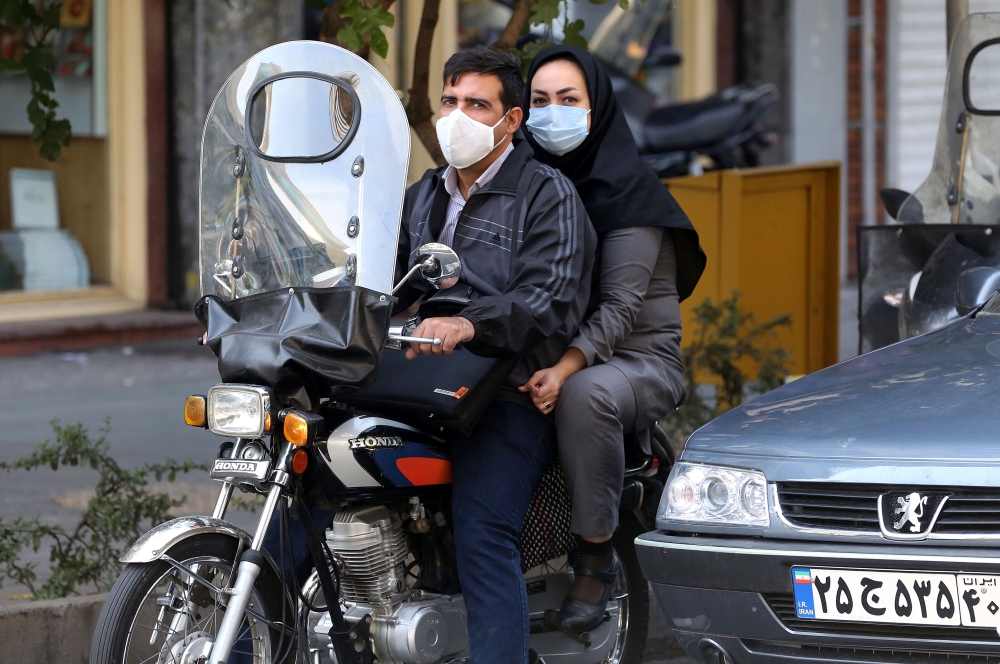 Iranians wear face masks as a COVID-19 coronavirus pandemic precaution, in Iran's capital Tehran on October 14, 2020. / AFP / ATTA KENARE