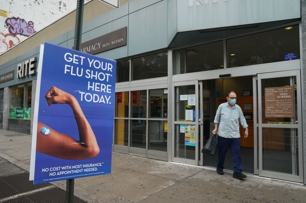 (FILES) In this file photo taken on August 19, 2020 a man walks past a free flu shot advertisement outside of a drugstore in New York. AFP / Bryan R. Smith