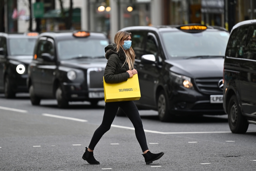 A woman wearing a protective face covering passes parked taxi cabs as she crosses Oxford Street in London, on October 17, 2020, as Londoners face more stringent novel coronavirus COVID-19 restrictions as the number of cases rises. AFP / JUSTIN TALLIS