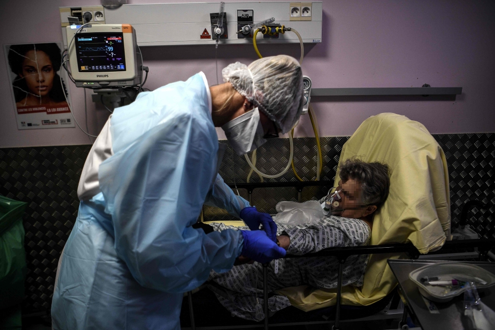 A nurse tends to an elderly woman suspected of being infected with Covid-19 at the emergency service of the Andre Gregoire hospital in Montreuil east of Paris on October 15, 2020. / AFP / Christophe ARCHAMBAULT
