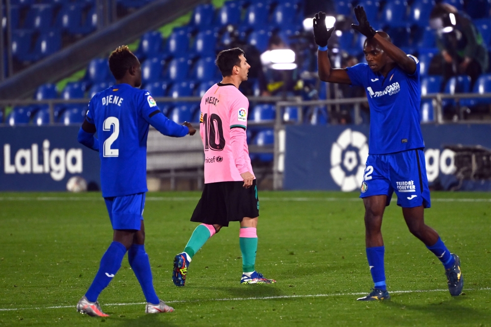 Getafe's Togolese defender Djene Dakonam (L) and Getafe's Cameroonian defender Allan Nyom (R) celebrate their victory as Barcelona's Argentine forward Lionel Messi walks past at the end of the Spanish League football match between Getafe and Barcelona at 
