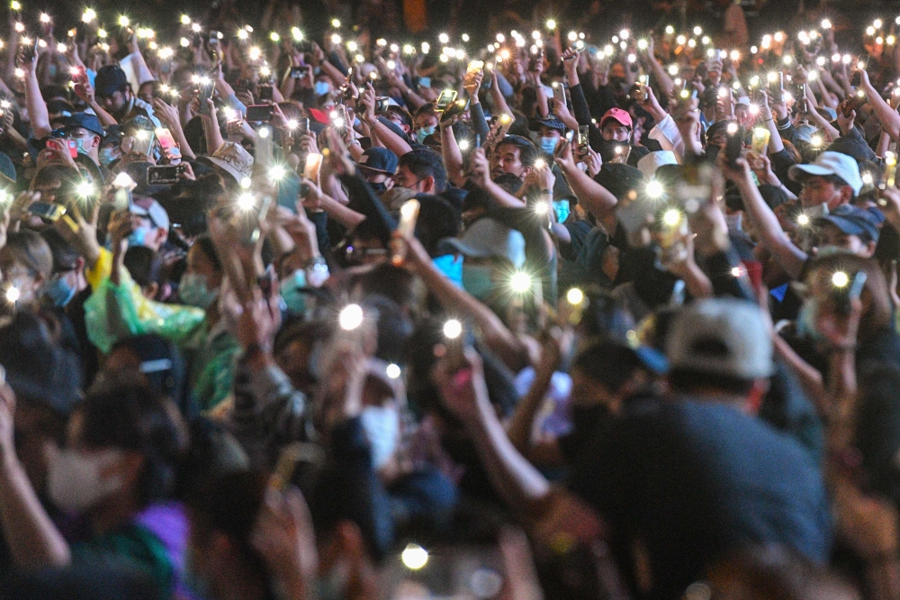 Pro-democracy protesters hold up their mobile phones with lights during an anti-government rally at Asok in Bangkok on October 18, 2020, as they continue for the fourth consecutive day to defy an emergency decree banning gatherings. / AFP / Mladen ANTONOV