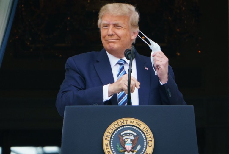 US President Donald Trump takes his mask off before speaking from the South Portico of the White House in Washington, DC during a rally. AFP / MANDEL NGAN
