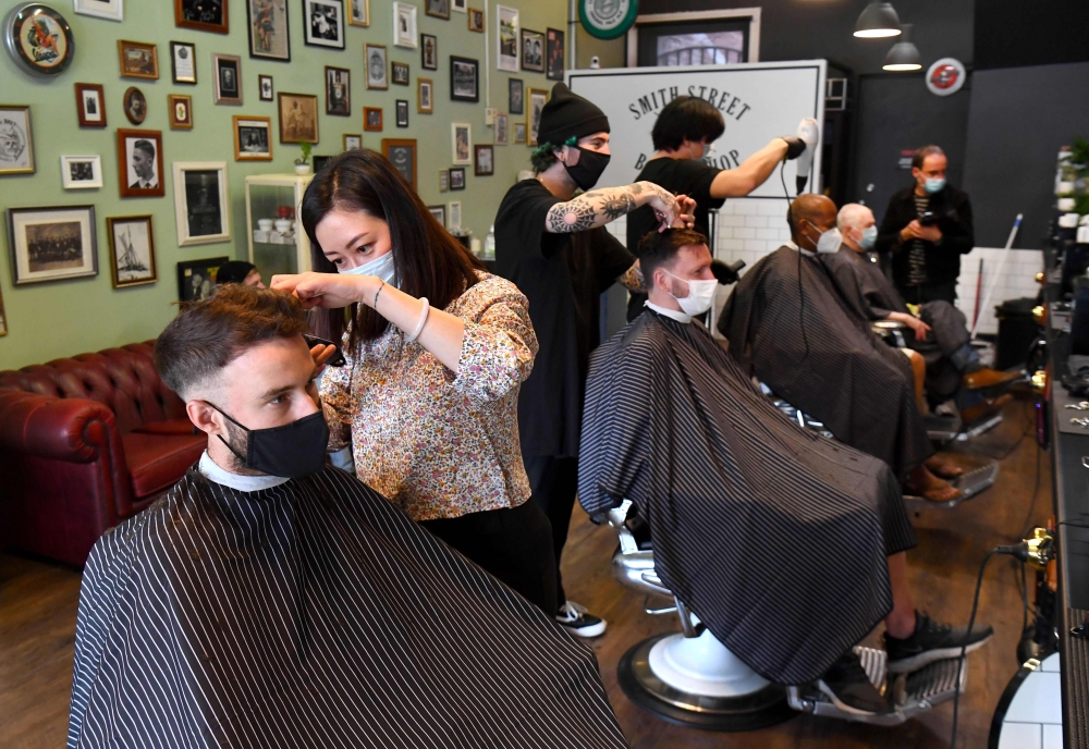 Men have their haircut at a barber shop in Melbourne on October 19, 2020, as some of the city's three-month-old stay-at-home restrictions due to the COVID-19 coronavirus outbreak were further eased on falling infection rates. AFP / William West 
