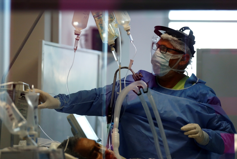 Nurse David Rosas checks a patient suffering from the coronavirus disease (COVID-19) in an intensive care unit of a hospital, on the outskirts of Buenos Aires, Argentina October 16, 2020. Picture taken October 16, 2020. REUTERS/Agustin Marcarian