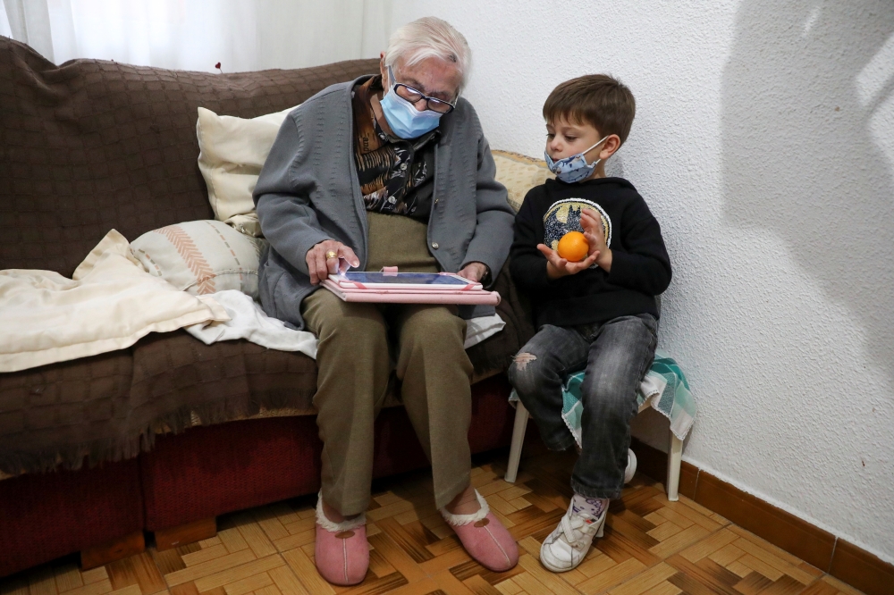 Florentina Martin, a 99-year-old woman who survived coronavirus disease (COVID-19), plays a digital puzzle with her great-grandson Pedro Valle at her home in Pinto, near Madrid, Spain, October 20, 2020. Picture taken October 20, 2020. Reuters/Sergio Perez