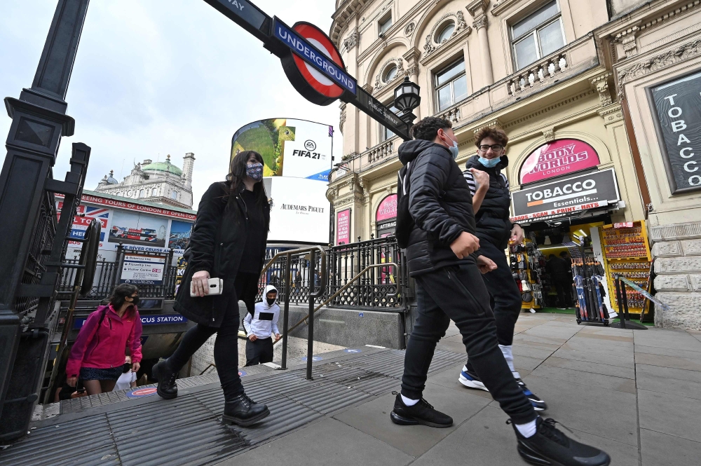 People wearing face masks or coverings due to the COVID-19 pandemic, react as they exit an Underground station in London on October 20, 2020. AFP / JUSTIN TALLIS