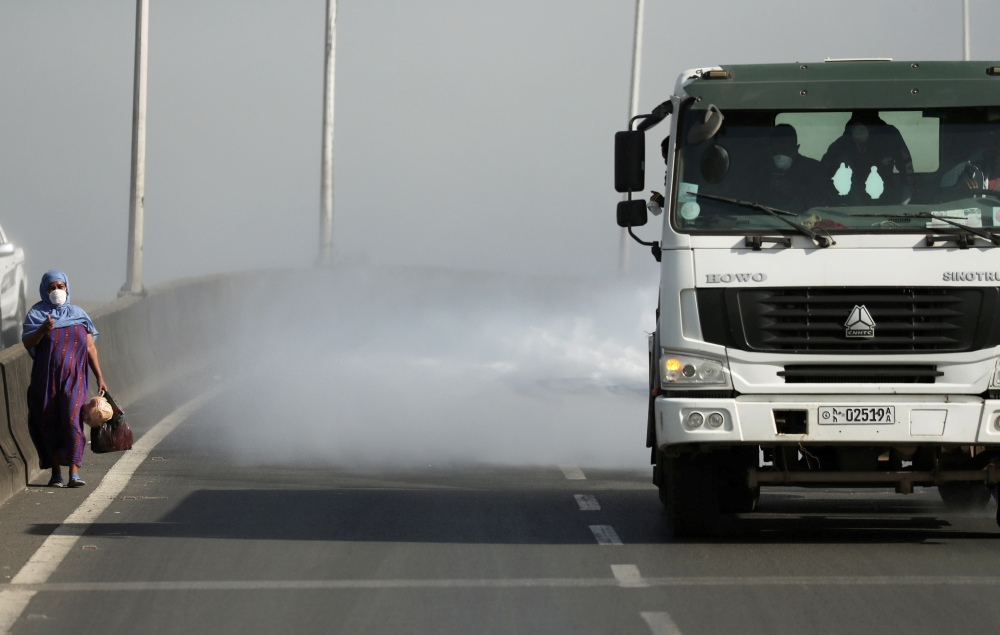 FILE PHOTO: A woman wearing a face mask walks next to a truck spraying disinfectant on the street as part of measures to prevent the potential spread of coronavirus (COVID-19), in Addis Ababa, Ethiopia March 29, 2020. REUTERS/Tiksa Negeri/File Photo