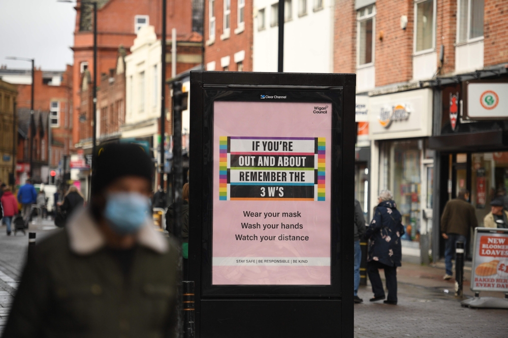 People wearing masks because the novel coronavirus pandemic walk in the high street in Leigh, Greater Manchester, northwest England on October 22, 2020 ahead of new coronavirus restrictions coming into force in the area. AFP / Oli SCARFF
