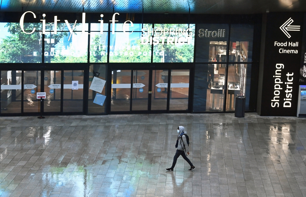 A person wearing a face mask walks at a shopping mall ahead of weekend closure of shopping centres, a measure imposed by the Lombardy region to curb the coronavirus disease (COVID-19) infections, in Milan, Italy, October 23, 2020. REUTERS/Flavio Lo Scalzo
