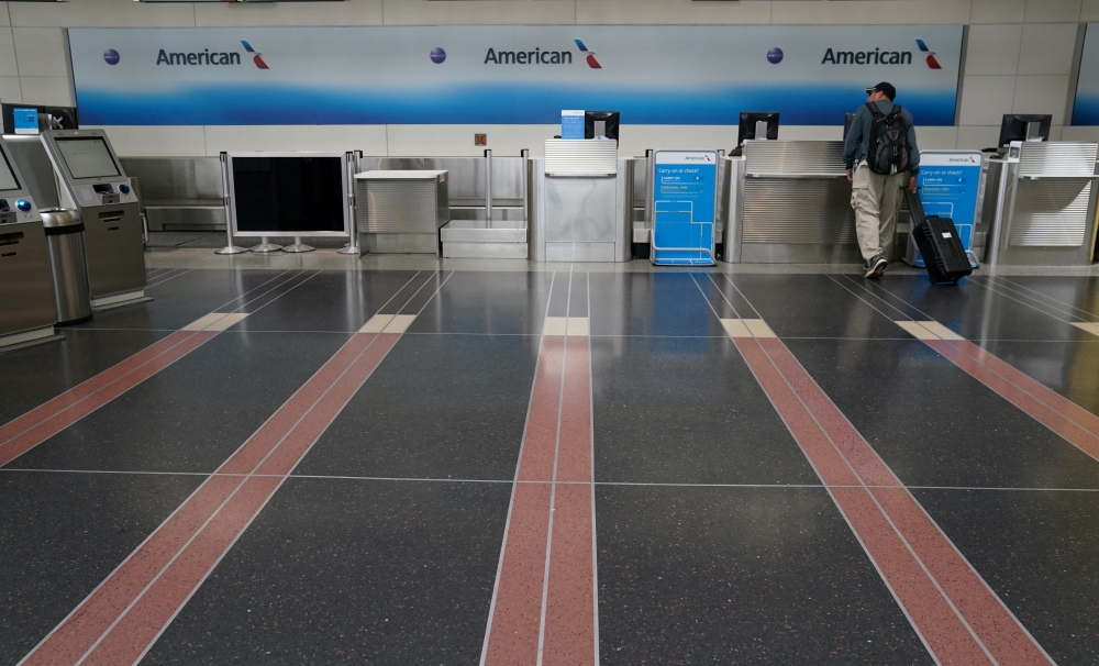 FILE PHOTO: A lone customer seeks assistance at an American Airlines check-in counter at Washington's Reagan National airport as the novel coronavirus (COVID-19) pandemic continues, in Washington, U.S. April 29, 2020. REUTERS/Kevin Lamarque/File Photo