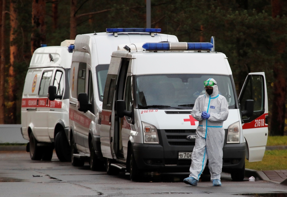 A medical specialist wearing protective gear stands next to ambulances parked outside a hospital amid the outbreak of the coronavirus disease (COVID-19) in Saint Petersburg, Russia October 23, 2020. REUTERS/Anton Vaganov