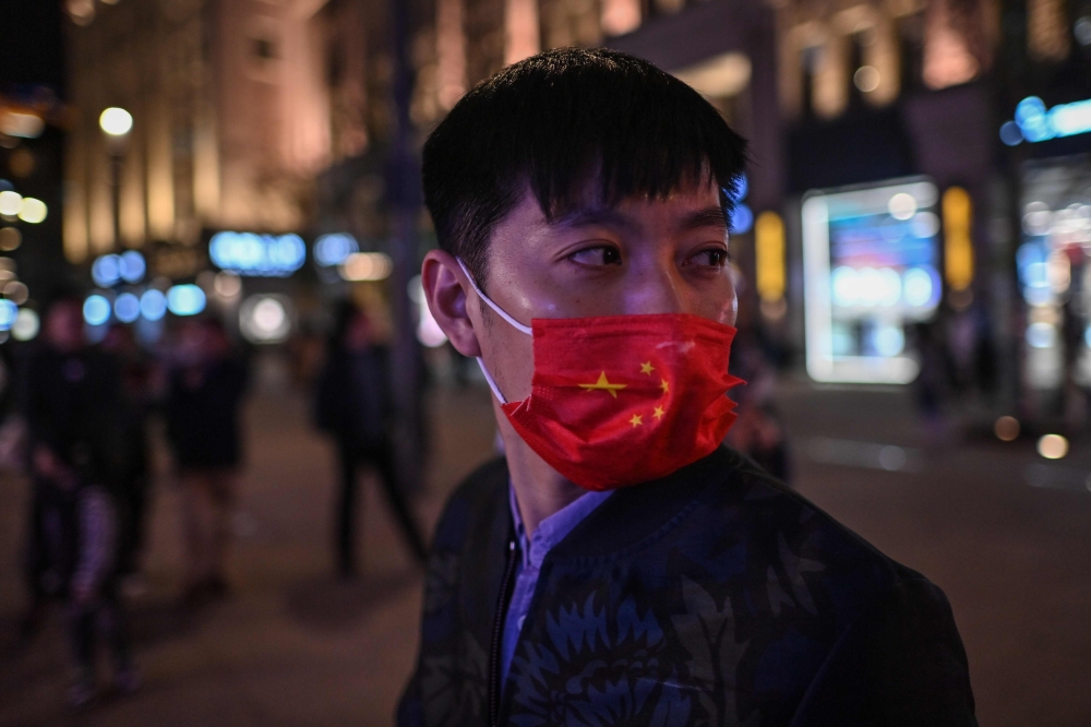 A man wearing a face mask as a preventive measure against the Covid-19 coronavirus walks along a pedestrian street in Shanghai on October 23, 2020. / AFP / Hector RETAMAL