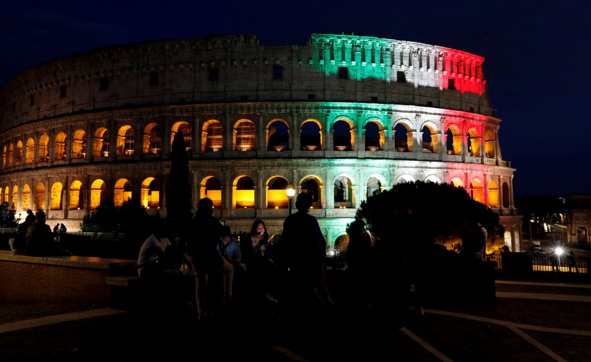 FILE PHOTO: People sit in front of Rome's ancient Colosseum illuminated with colours of the Italian flag in Rome, Italy, May 31, 2020. REUTERS/Remo Casilli/File Photo
