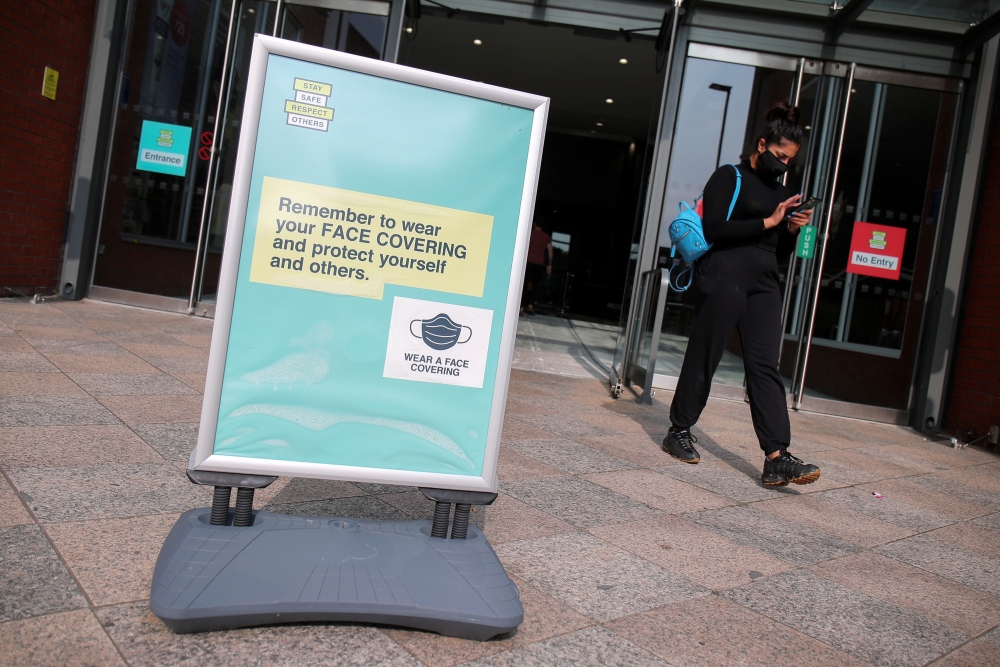 A woman wearing a protective mask walks near an informational poster, amid the coronavirus disease (COVID-19) outbreak, in Warrington, Britain September 22, 2020. REUTERS/Molly Darlington/File Photo