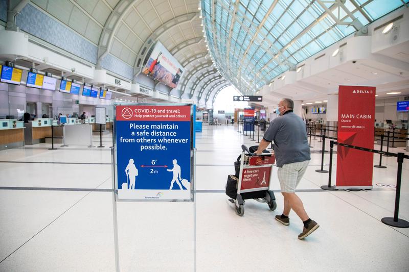FILE PHOTO: A man pushes a baggage cart wearing a mandatory face mask as a 