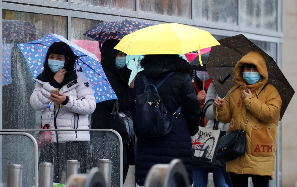People wearing face masks shelter under umbrellas outside a department store following the outbreak of the coronavirus disease (COVID-19) in Manchester, Britain, October 26, 2020. REUTERS/Phil Noble/File Photo