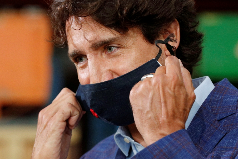 FILE PHOTO: Canada's Prime Minister Justin Trudeau removes his face mask before speaking at the 3M's plant in Brockville, Ontario, Canada August 21, 2020. REUTERS/Lars Hagberg/File Photo
