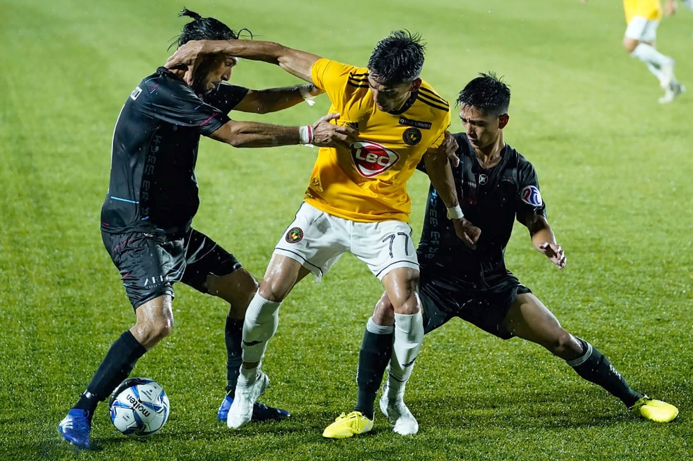 This handout photo taken on October 28, 2020 and received on October 29 from the Philippine Football League (PFL) shows Jason Panhay (C) of Kaya FC-Iloilo being tackled by players from Maharlika Manila FC during their Philippine Football League football m