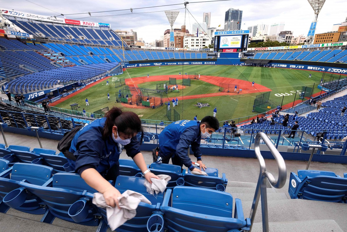 Workers take cleaning seats of the Yokohama Stadium, which will host baseball and softball games during the Tokyo Olympics, prior to a professional baseball game in Yokohama, Kanagawa prefecture on October 30, 2020. / AFP / Kazuhiro NOGI
