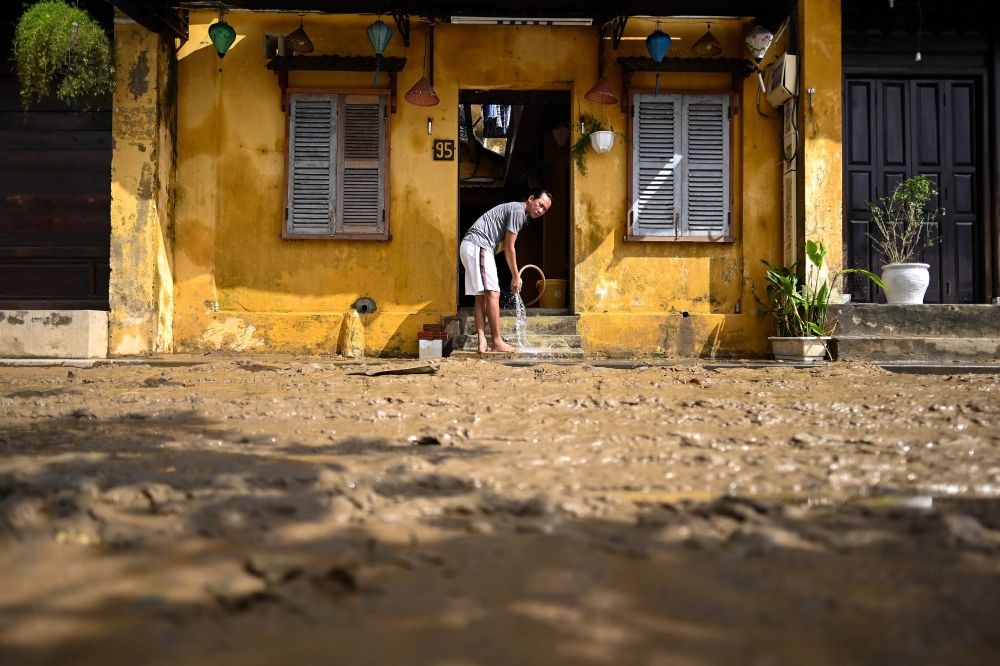 A man cleans up mud inside his house after waters receded in the old city of Hoi An, a UNESCO world heritage site, on October 30, 2020, in the aftermath of Typhoon Molave. / AFP / Manan VATSYAYANA