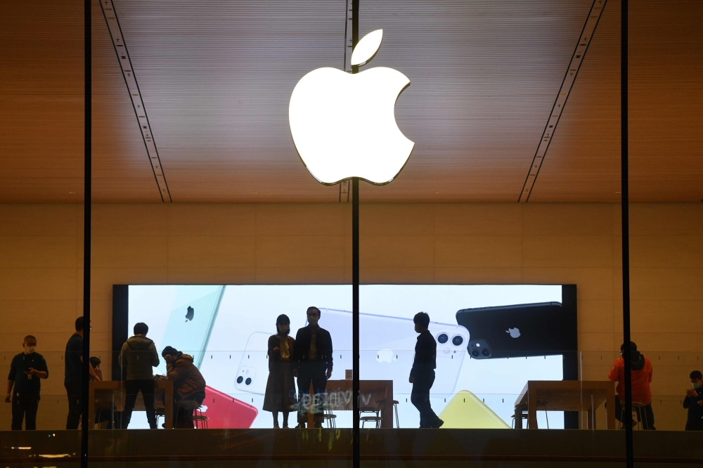 In this file photo taken on October 19, 2020 people walk inside an Apple store in Beijing. A steep drop in iPhone sales in the latest quarter cut Apple's profit by 7 percent to $12.7 billion, the company announced October 29, 2020, sending the company's s