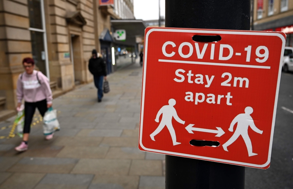 Shoppers walk past a sign displaying Covid-19 guidelines, in Bradford, west Yorkshire on October 31, 2020, as the number of cases of the novel coronavirus COVID-19 rises. AFP / Paul Ellis