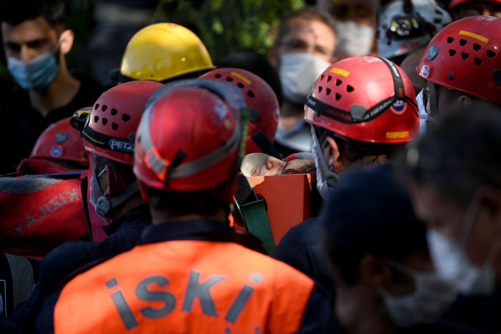 Search and rescue teams carry Sefer Perincek, mother of three, on a stretcher after pulling her out of the rubble of a collapsed building on October 31, 2020, in Izmir. AFP / OZAN KOSE