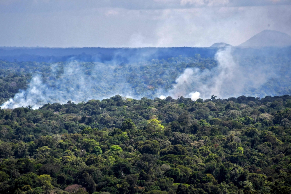 Aerial view showing smoke from a fire billowing from the Amazon rainforest in Oiapoque, Amapa state, Brazil, on the border with French Guiana, on October 31, 2020./ AFP / NELSON ALMEIDA
