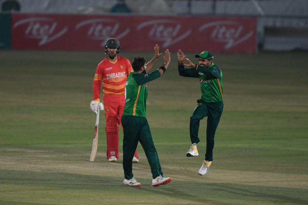 Pakistan's captain Babar Azam (R) celebrates with teammate Imad Wasim (C) the dismissal of Zimbabwe's Craig Ervine during the first one-day international (ODI) cricket match between Pakistan and Zimbabwe at the Rawalpindi Cricket Stadium in Rawalpindi on 