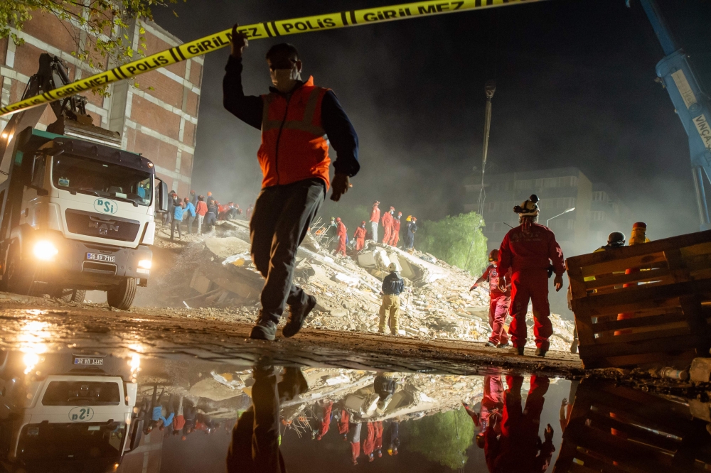 Rescue workers search for survivors in the debris of a collapsed building on November 1, 2020 in the Bayrakli district of Izmir, after a powerful earthquake struck Turkey's western coast and parts of Greece. Rescue workers were searching eight buildings i