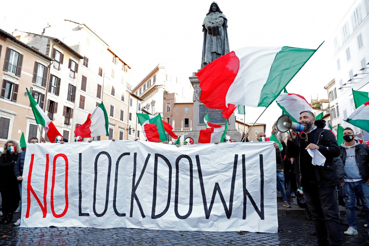 People hold a banner and Italian flags as they protest against the government's restrictive measures imposed to combat the rising number of the coronavirus disease (COVID-19) infections, in Campo De' Fiori, Rome, Italy October 31, 2020. REUTERS/Remo Casil